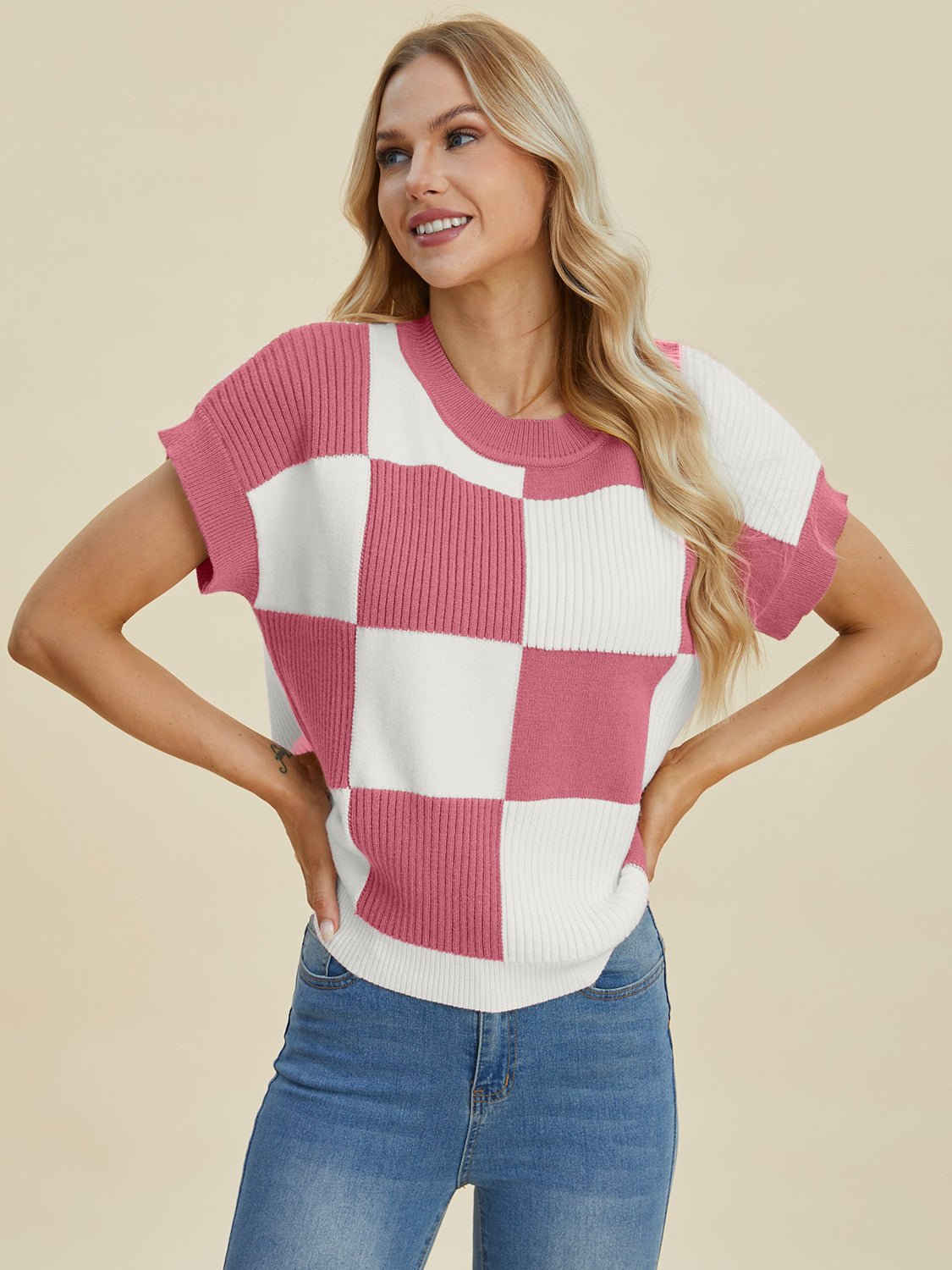 Woman wearing a checkered round neck short sleeve sweater in pink and white, made of viscose, polyester, and polyamide.