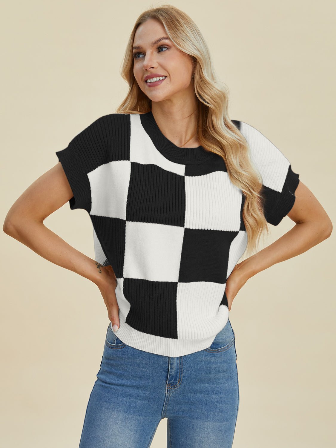 Woman wearing a checkered round neck short sleeve sweater with blue jeans.