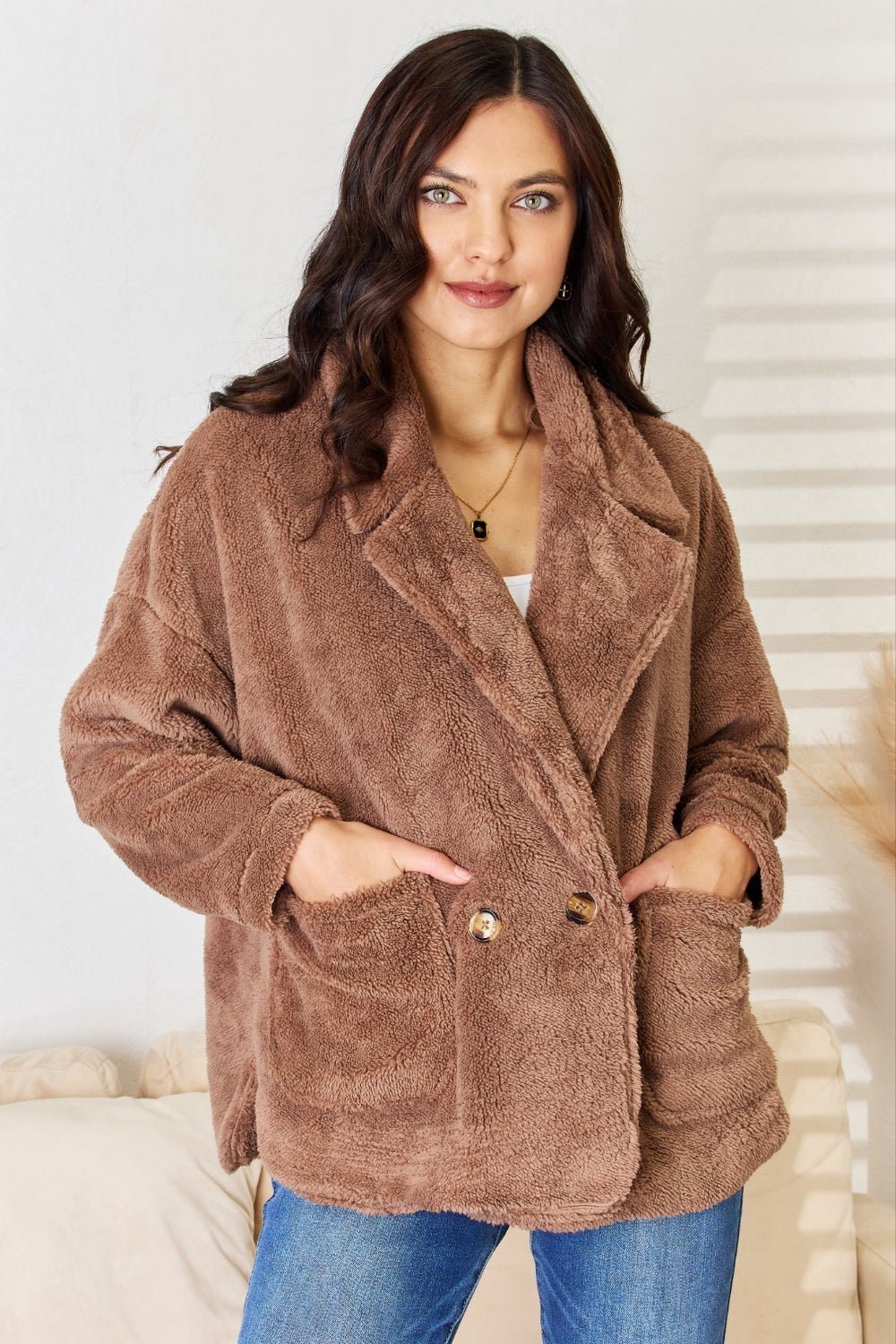 Woman wearing brown double-breasted fuzzy coat made of 100% polyester, showcasing cozy style and warm texture.