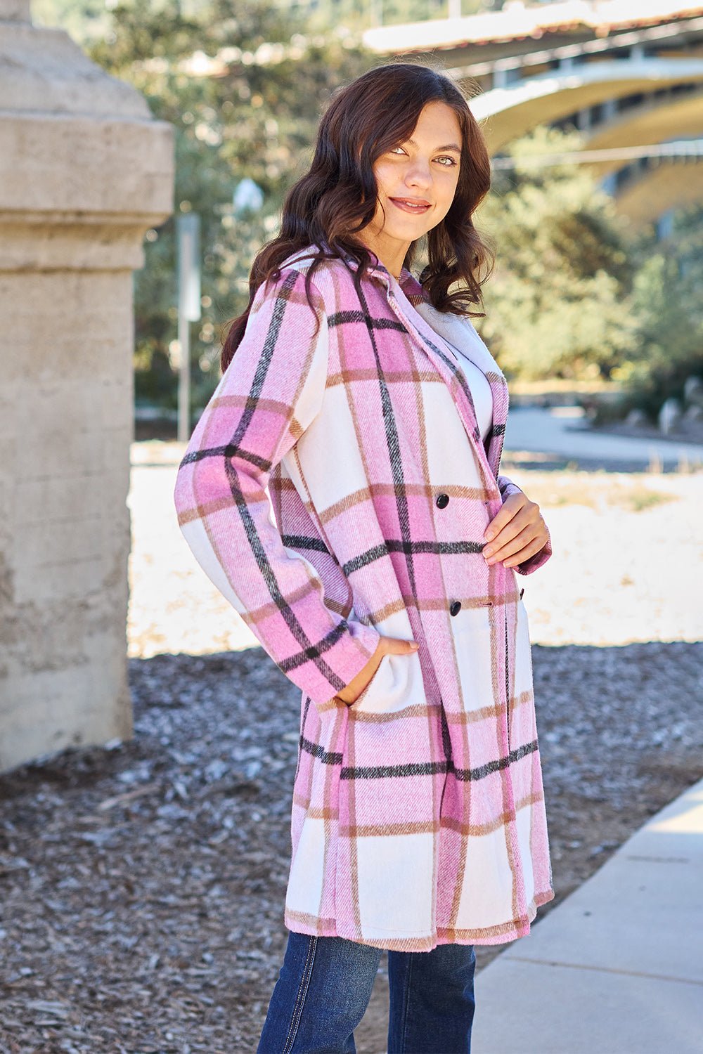 Woman wearing a full size plaid button-up lapel collar coat with pockets, made from 100% polyester, outdoors on a sunny day.