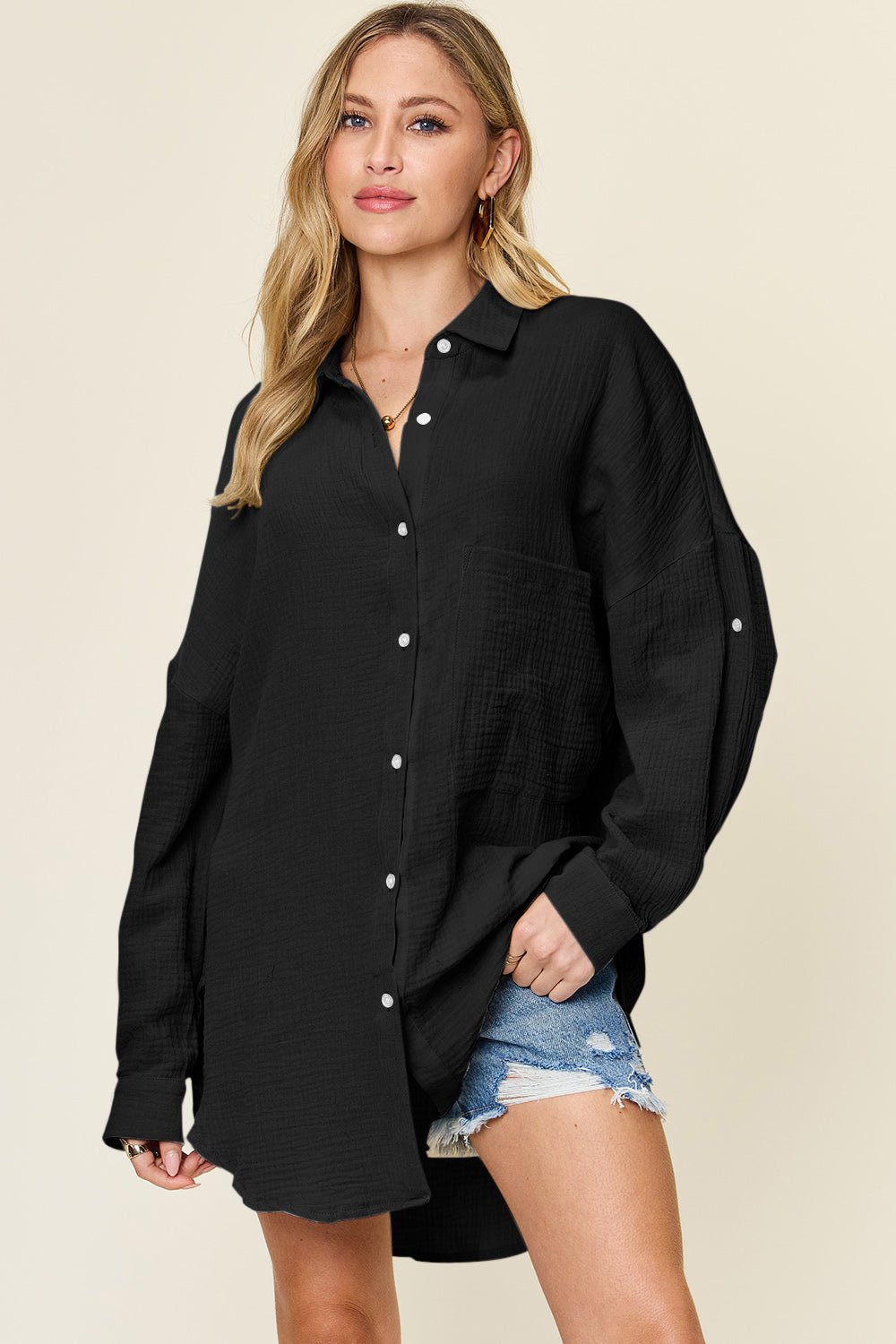 Woman wearing a full-size black pocketed texture button-up shirt made of 100% cotton, paired with denim shorts.