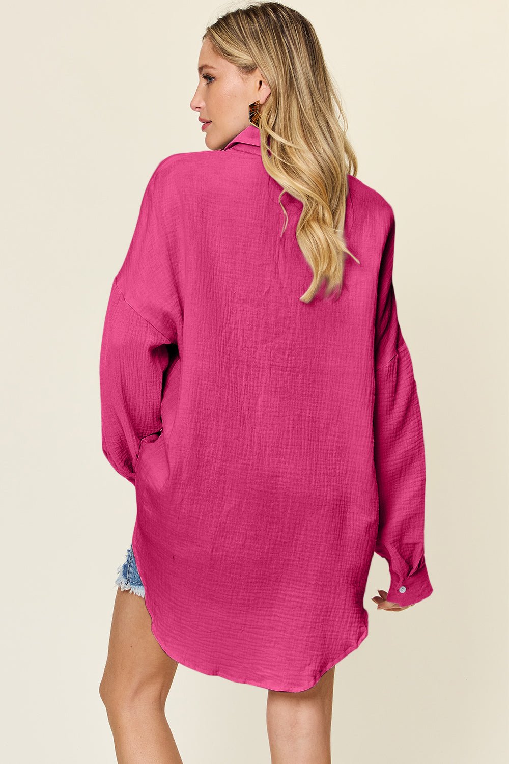 Woman wearing full size pocketed texture button-up shirt in vibrant pink, showcasing the back detail, slightly stretchy and 100% cotton.