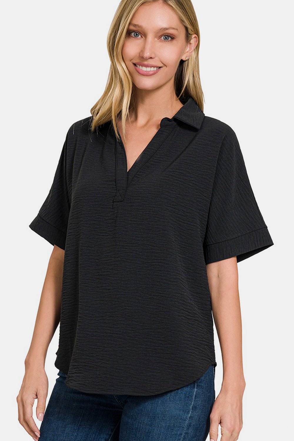 Woman wearing a black full size texture collared neck short sleeve top made of 100% polyester, paired with blue jeans.