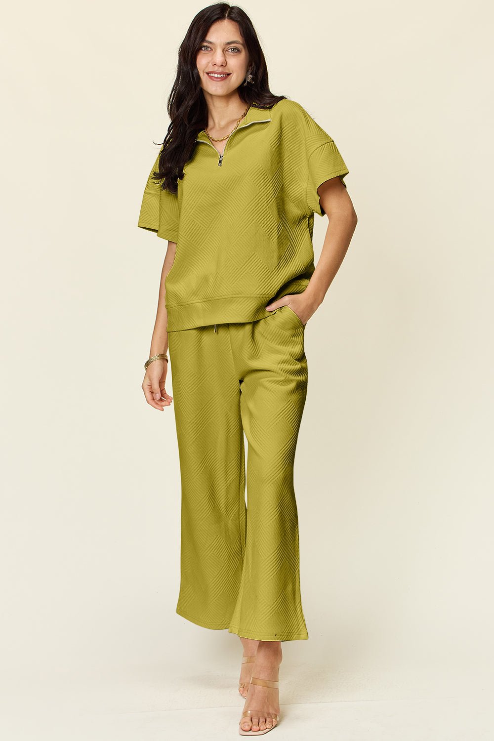 Woman wearing full size texture half zip short sleeve top and pants set in green, featuring pockets and drawstring.
