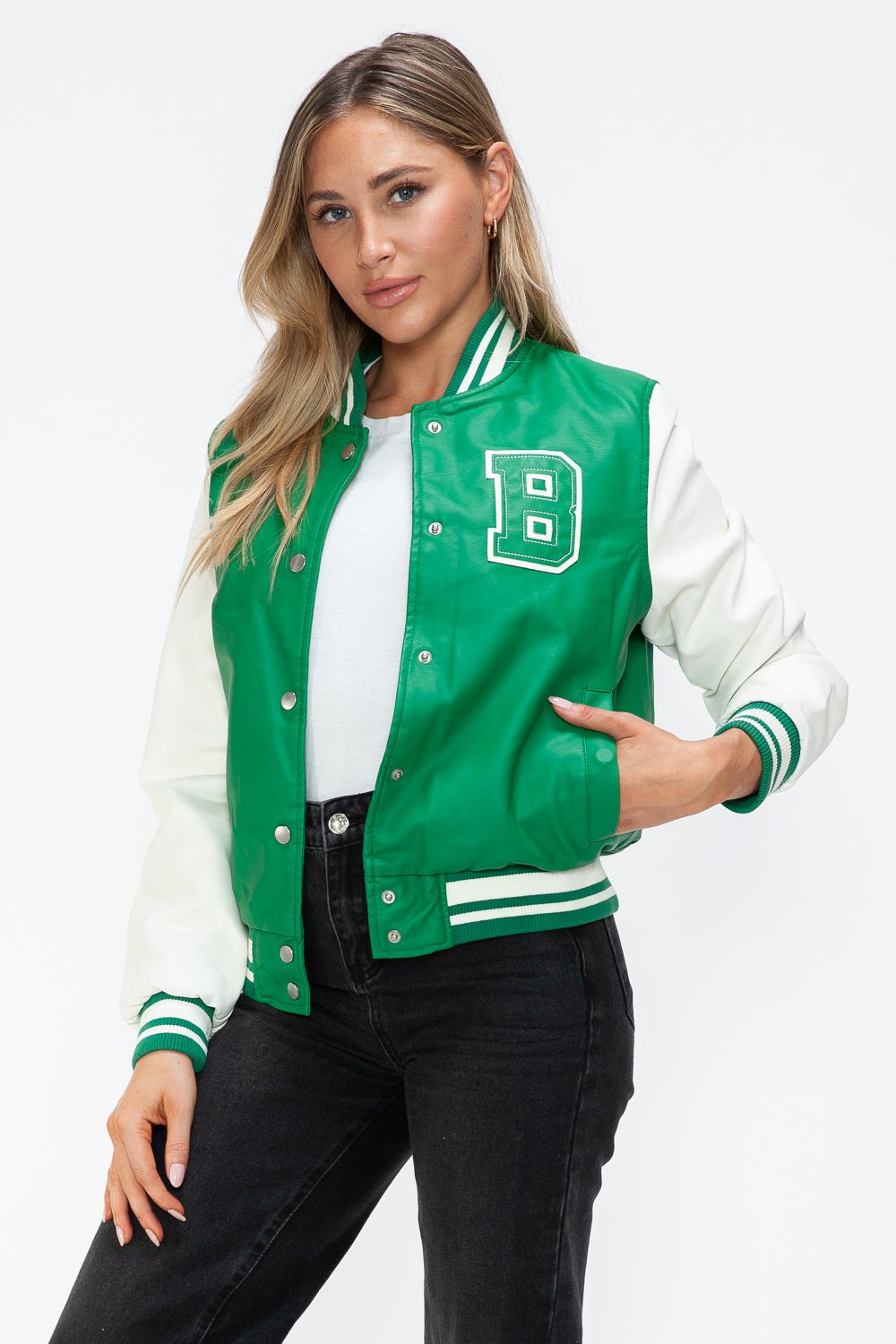 Woman wearing a green PU leather contrast snap down bomber jacket with white sleeves and varsity style "B" patch.