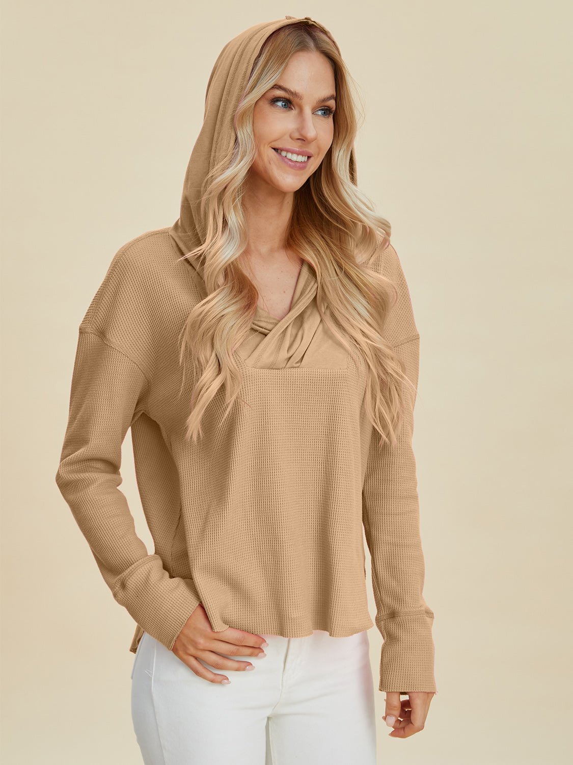 Woman wearing beige high-low dropped shoulder long sleeve hoodie with slight stretch, made of 65% polyester and 35% cotton
