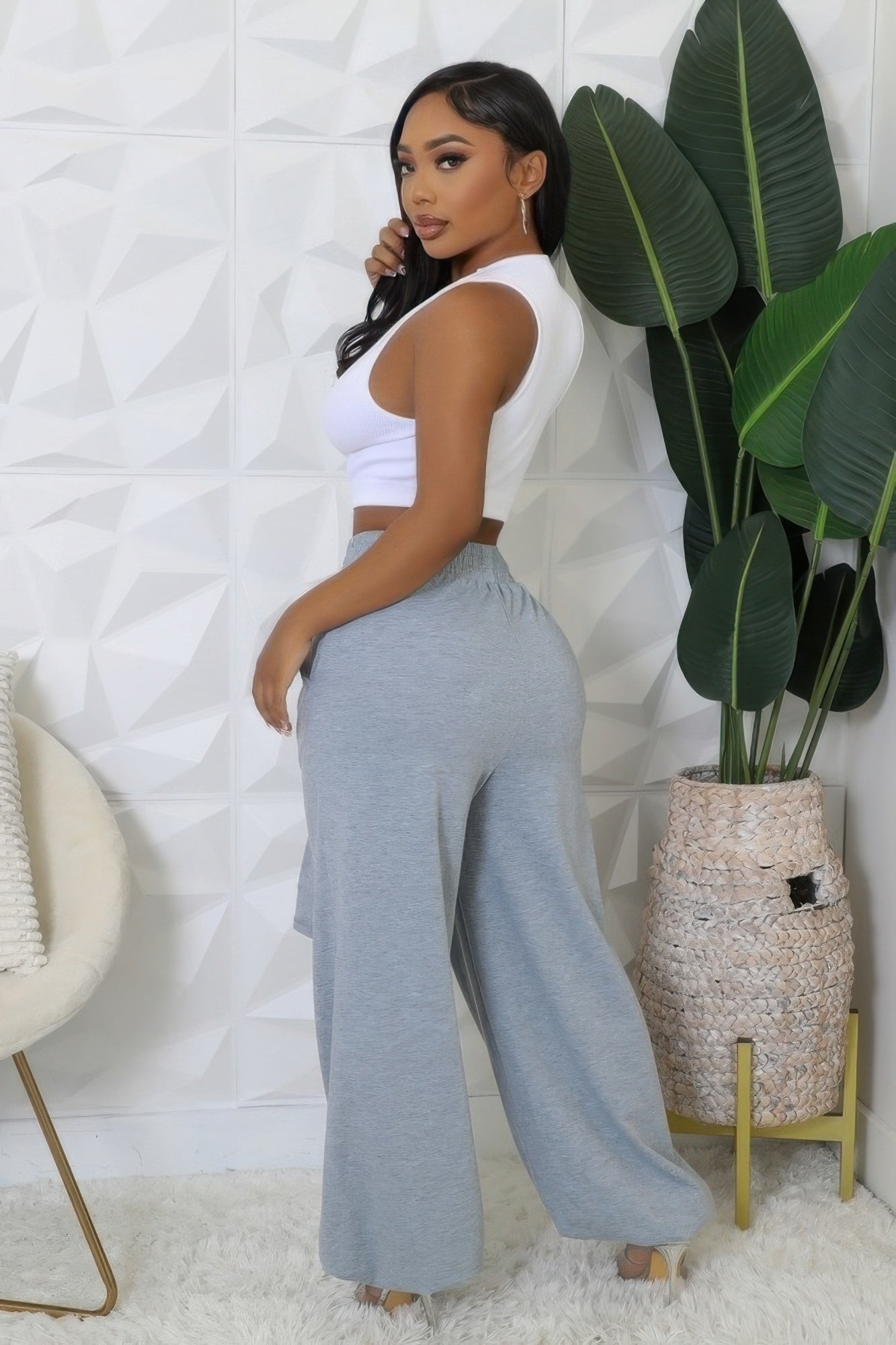 Woman wearing high-waisted stretch pants with a comfortable elastic waistband and cuffed bottoms, styled in a modern indoor setting.