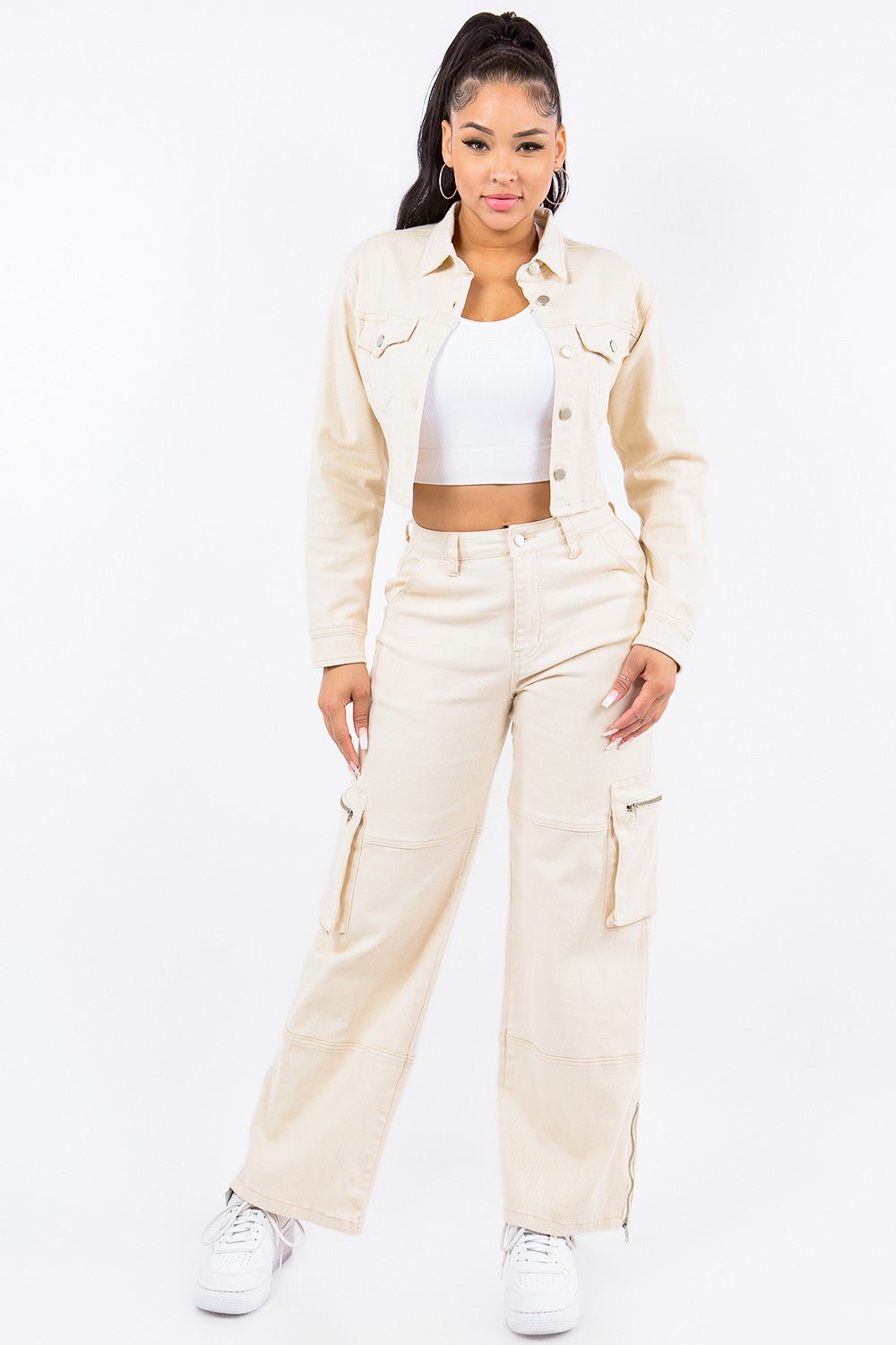 Woman wearing stylish beige cropped jacket and matching wide-leg trousers, paired with a white top and sneakers.