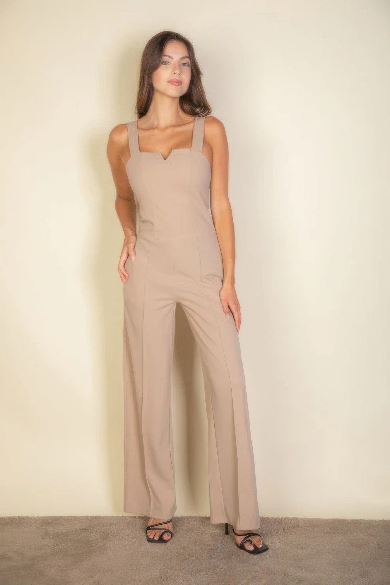 Woman wearing notched neck taupe cami jumpsuit, showcasing a chic fit, perfect for versatile styling and all-day comfort.
