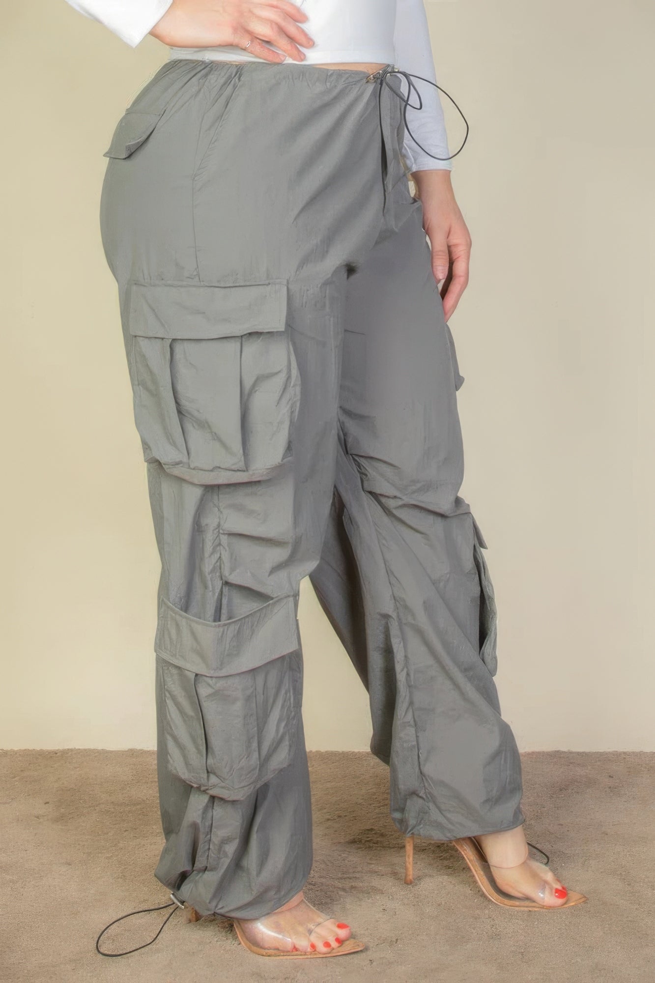 Plus Size Flap Pockets Drawstring Ruched Parachute Pants in gray with non-stretch fabric, shown on model wearing high heels.