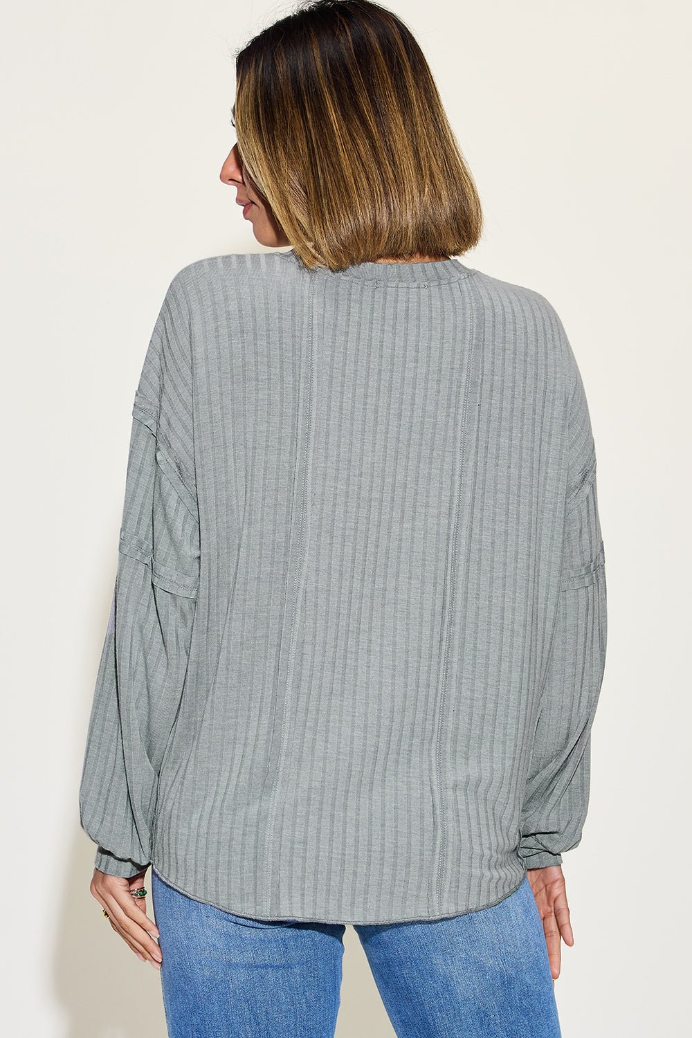 Ribbed round neck long sleeve t-shirt in gray with exposed seam design, worn by model, showcasing moderate stretch and casual style.