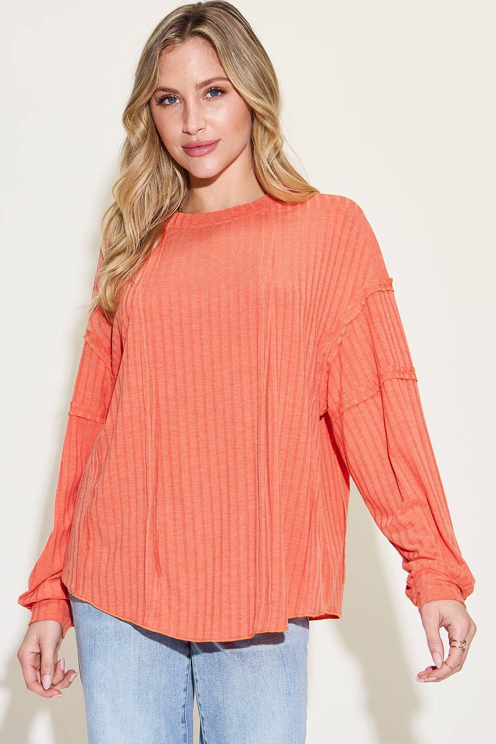 Ribbed round neck long sleeve T-shirt in orange with exposed seams and moderate stretch, worn by a model, basic style.