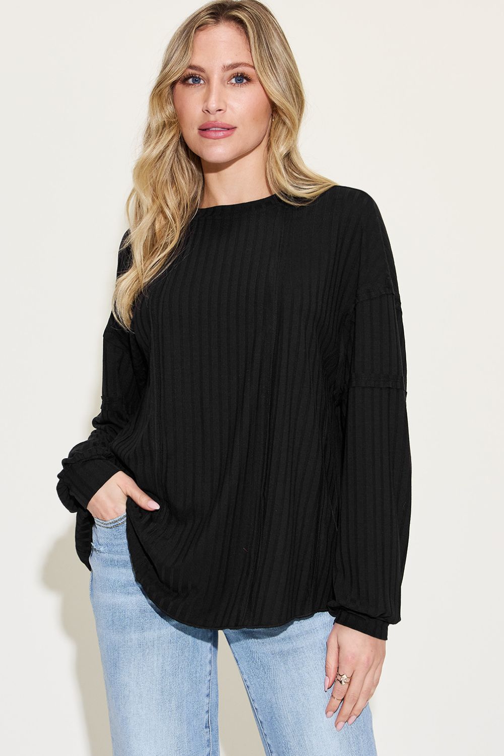 Woman wearing a black ribbed round neck long sleeve T-shirt with moderate stretch, paired with jeans.