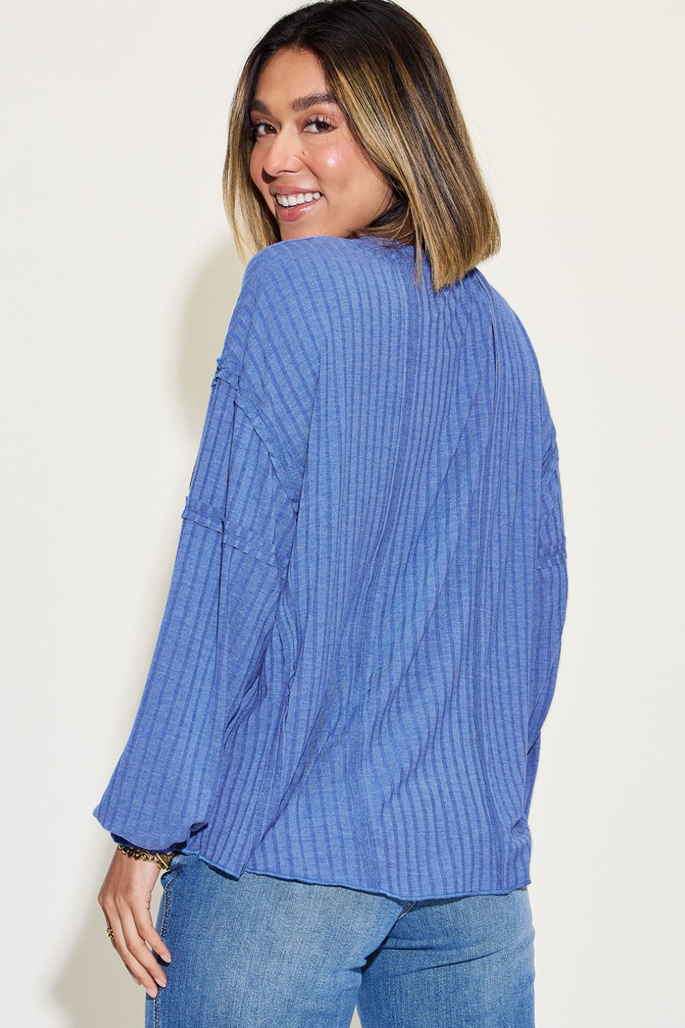 Woman wearing blue ribbed round neck long sleeve t-shirt with exposed seam and moderate stretch