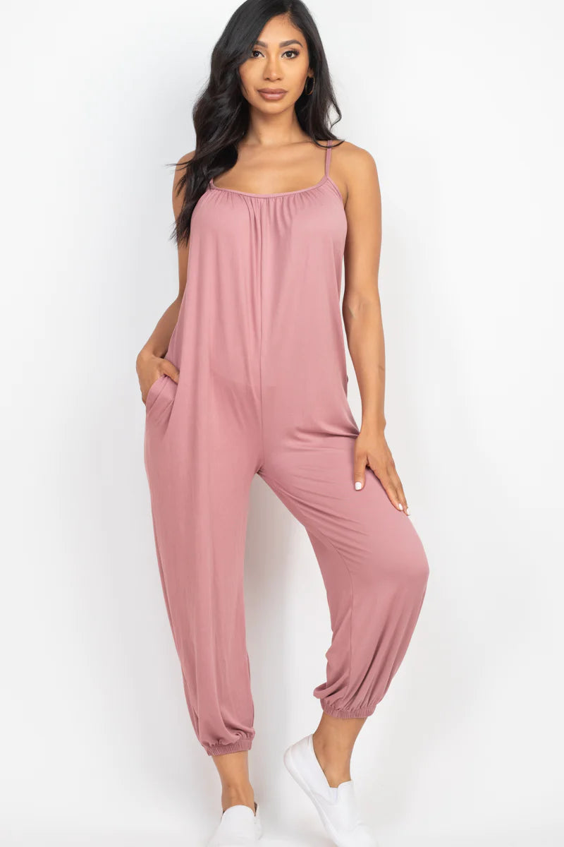 Woman wearing a sleeveless jogger jumpsuit with spaghetti straps, showcasing its soft, lightweight fabric and relaxed fit.