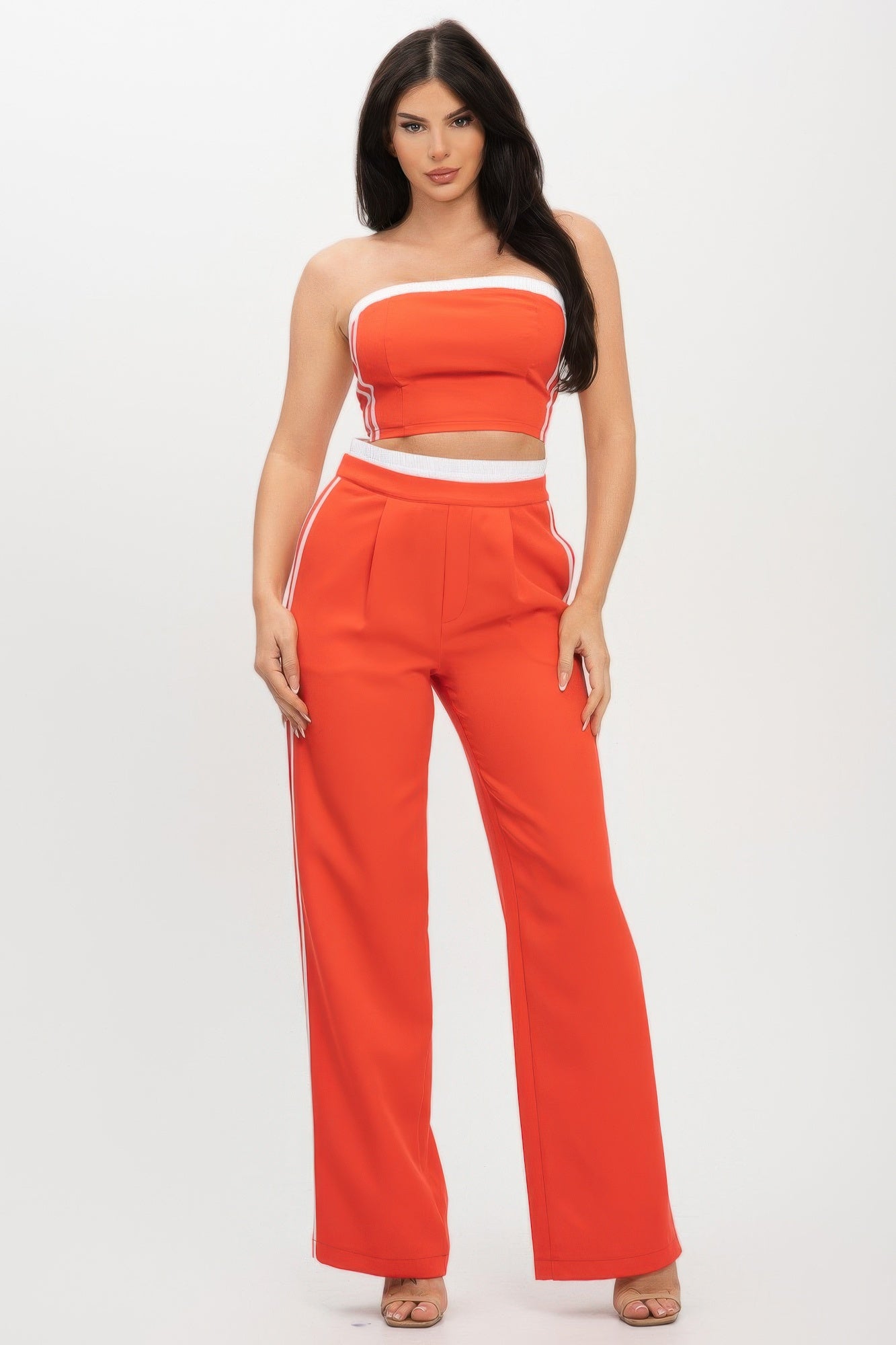 Woman in red and white two-piece athletic set with strapless crop top and wide-leg pants, standing against white background