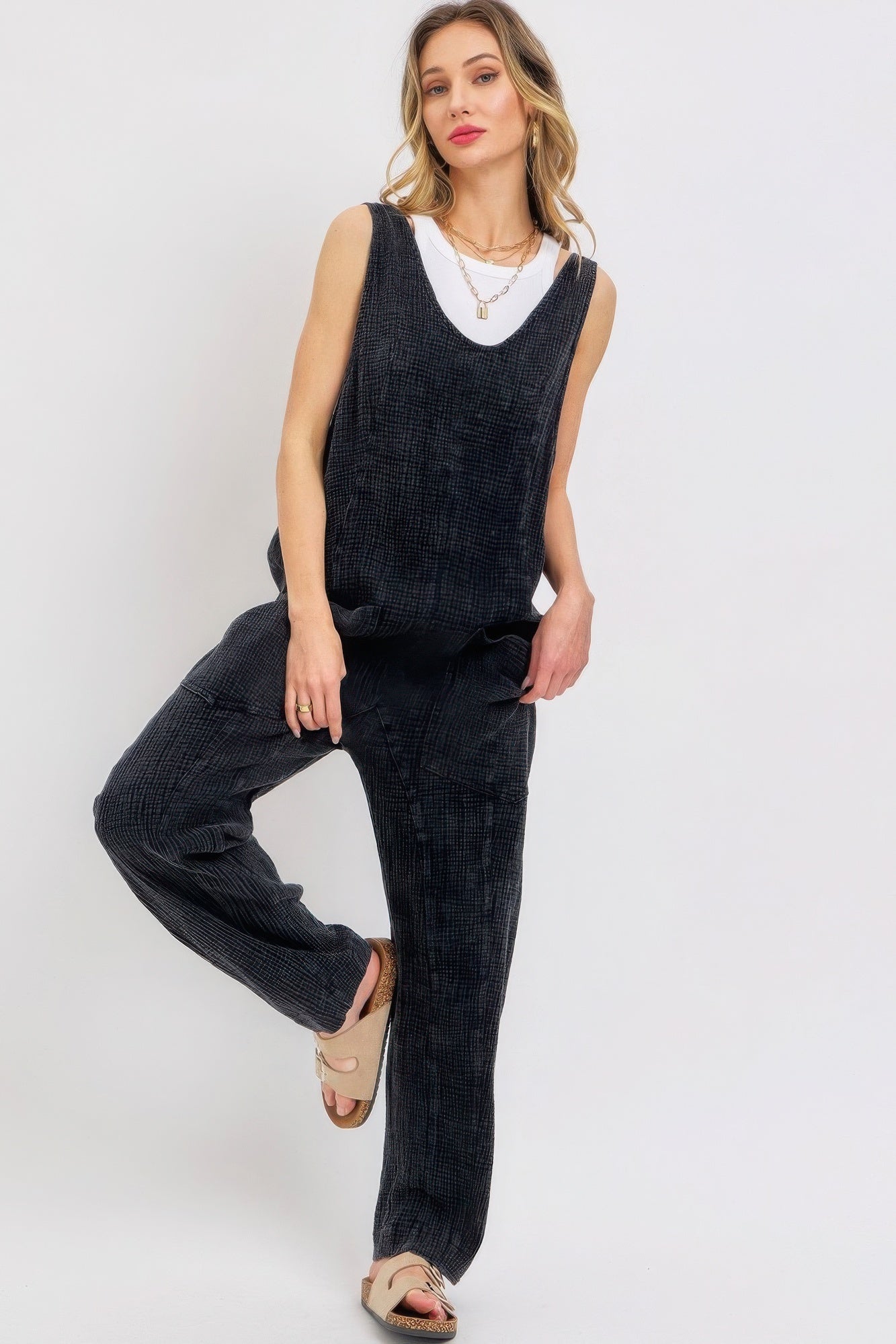 Woman wearing mineral washed summer jumpsuit with adjustable straps and oversized pockets, showcasing relaxed style and comfort.