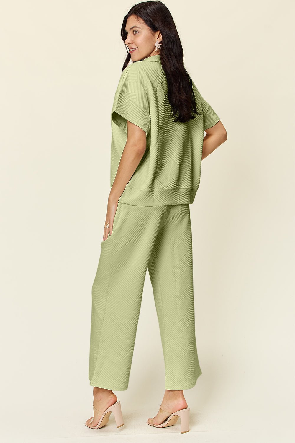 Woman wearing green texture half zip short sleeve top and pants set with pockets, showcasing a casual and stylish outfit.