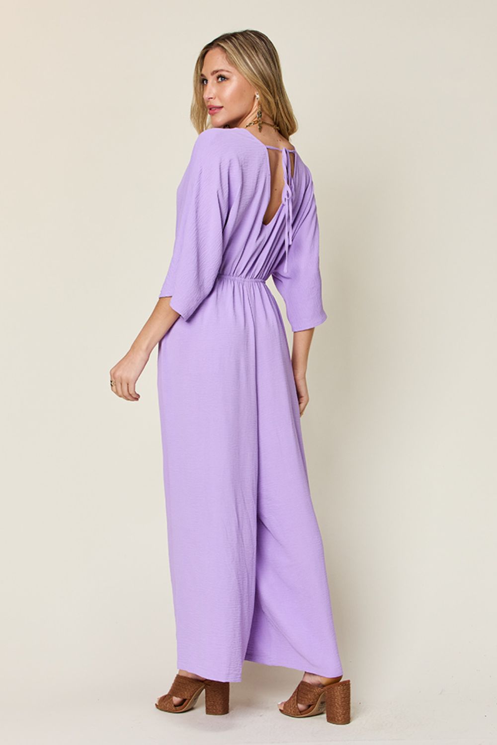 Lavender surplice wide leg jumpsuit with pockets, tied and ruched design, made of 95% polyester and 5% spandex.