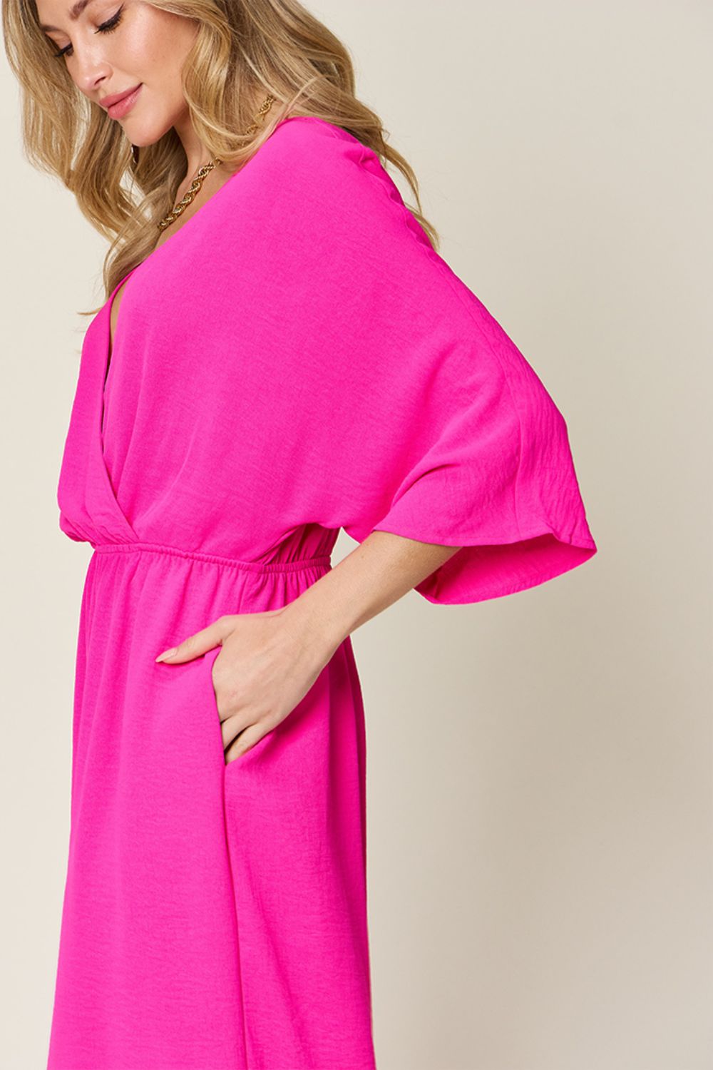Pink surplice wide leg jumpsuit with pockets, tied and ruched details, made from 95% polyester and 5% spandex.