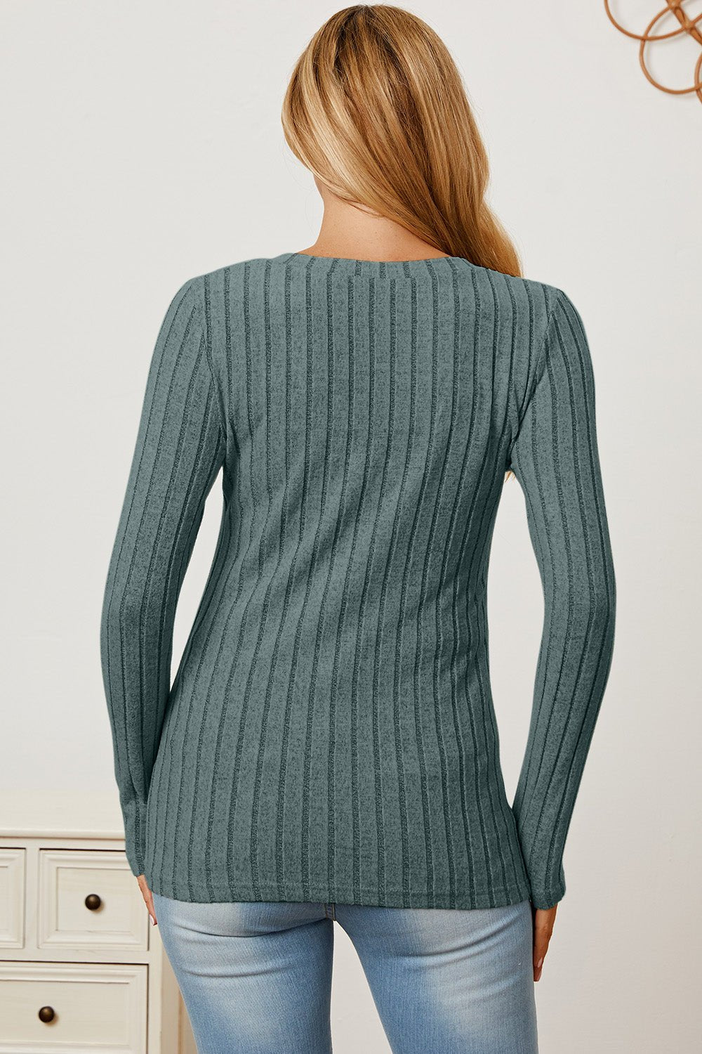 Woman wearing Basic Bae Ribbed V-Neck Long Sleeve T-Shirt in grey, showcasing back view, paired with light blue jeans.