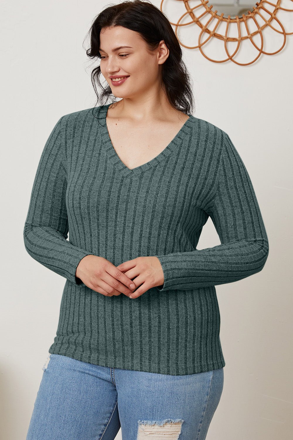 Woman wearing Basic Bae Full Size Ribbed V-Neck Long Sleeve T-Shirt in green, paired with ripped jeans.