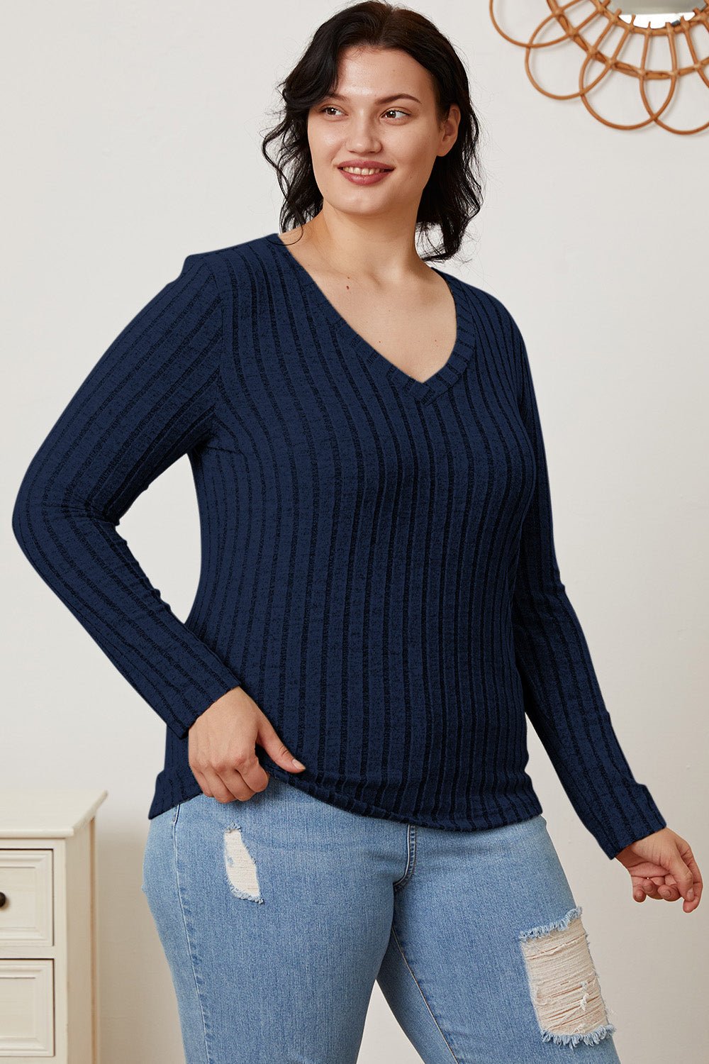 Woman wearing Basic Bae full-size ribbed V-neck long sleeve T-shirt in navy, paired with distressed jeans.