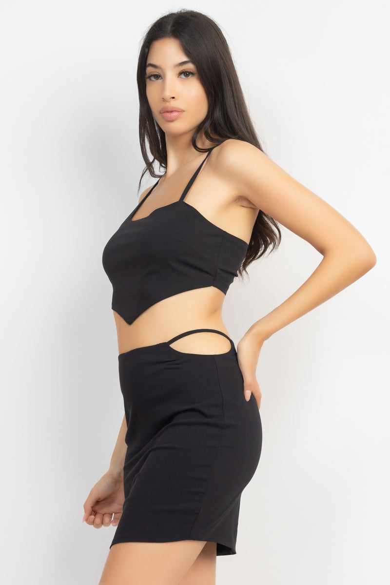Woman wearing Asymmetrical Cross Back Top & Skirts Set in black, featuring sleeveless scoop neck and high waist skirt with side cutouts.