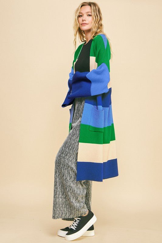 Woman wearing blue stripe color block kimono sleeve open front cardigan with pockets, styled casually with sneakers.