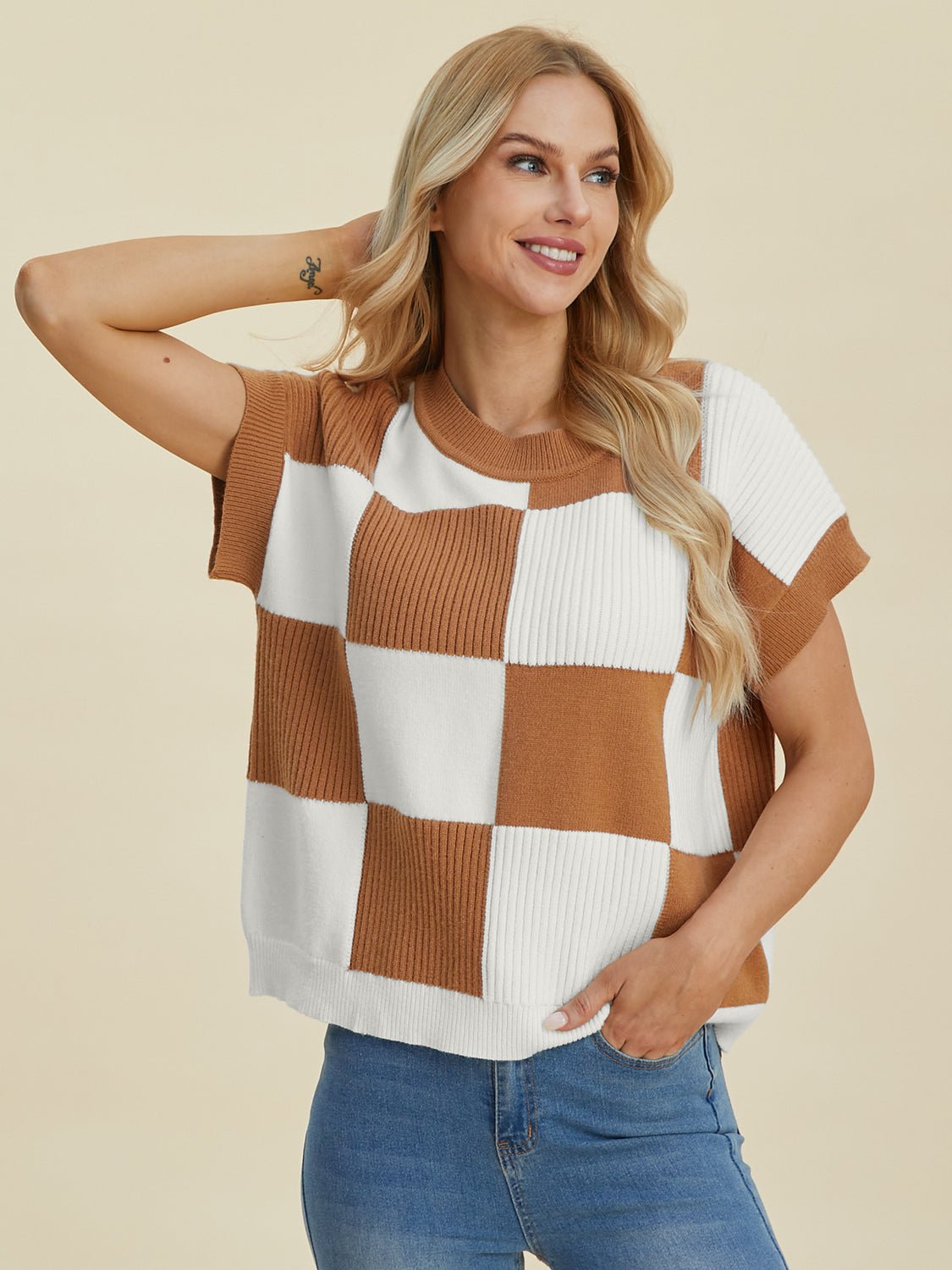 Woman wearing a checkered round neck short sleeve sweater in brown and white, slightly stretchy, made of viscose, polyester, polyamide.