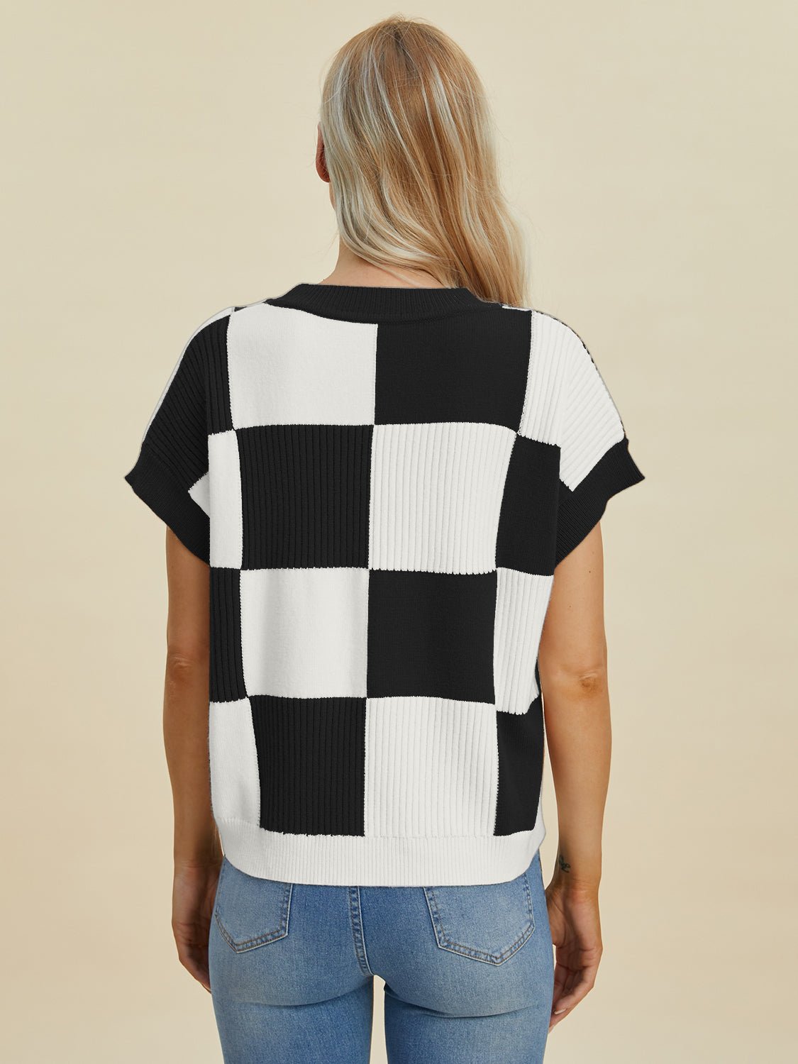 Woman wearing a black and white checkered round neck short sleeve sweater, showcasing its basic style and slight stretch feature.