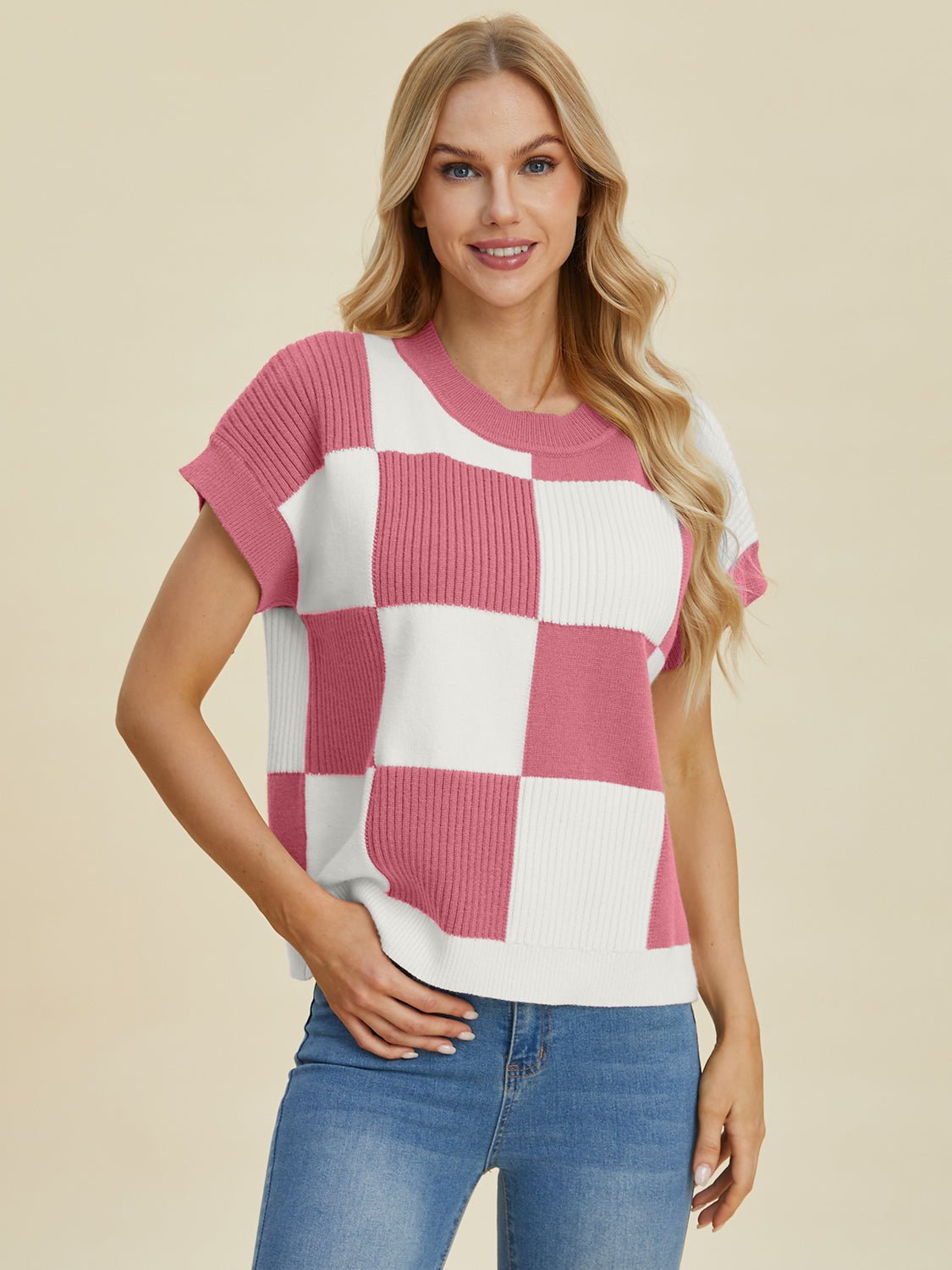 Woman wearing a pink and white checkered round neck short sleeve sweater with slightly stretchy fabric.