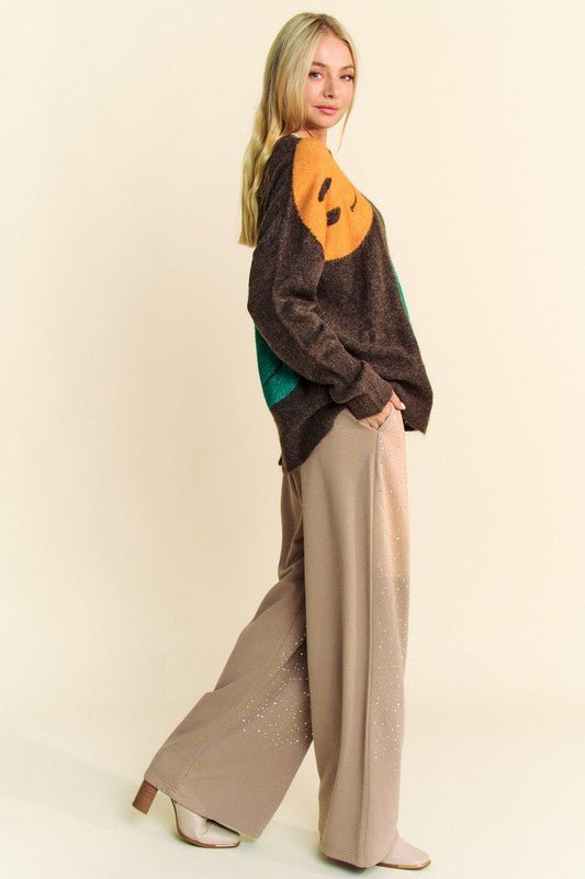 Woman wearing a contrast smile design round neck oversize sweater with loose beige pants, showcasing a trendy and casual fall outfit.