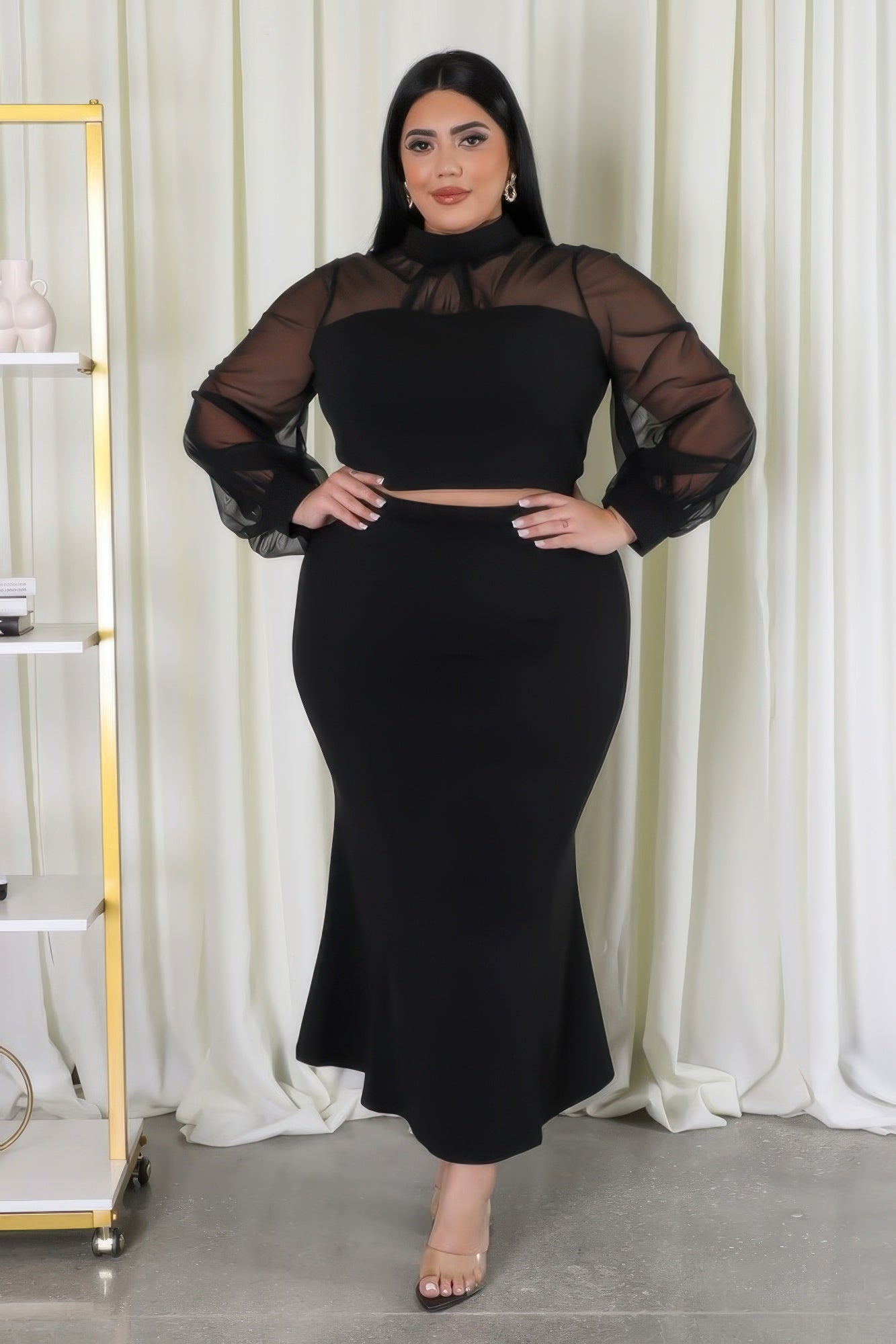 Black stretch skirt set with mesh accents and mock neckline, plus size model, showcasing chic and versatile fashion apparel.