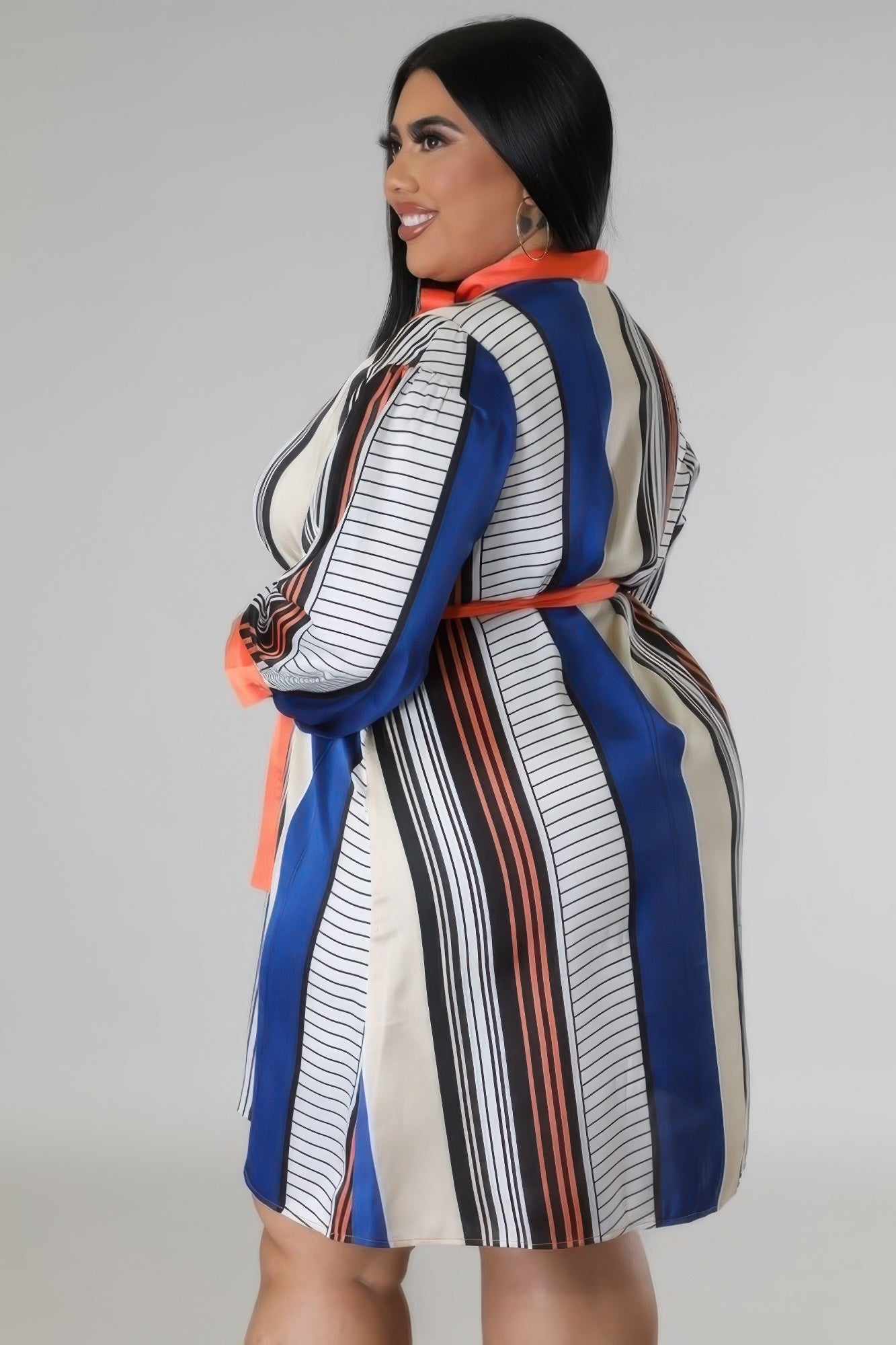 Woman in curvy long sleeves dress with blue, brown, and rust stripes, showcasing non-stretch polyester fabric.