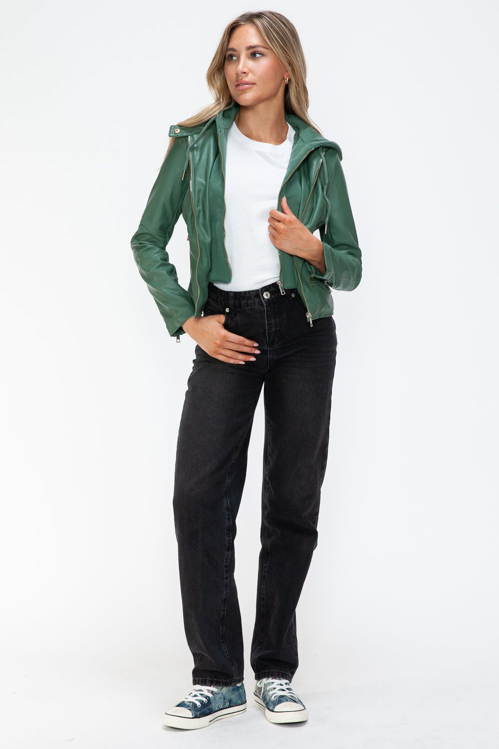 Woman wearing a green faux leather zip-up hooded jacket with drawstring, standing confidently in casual attire.