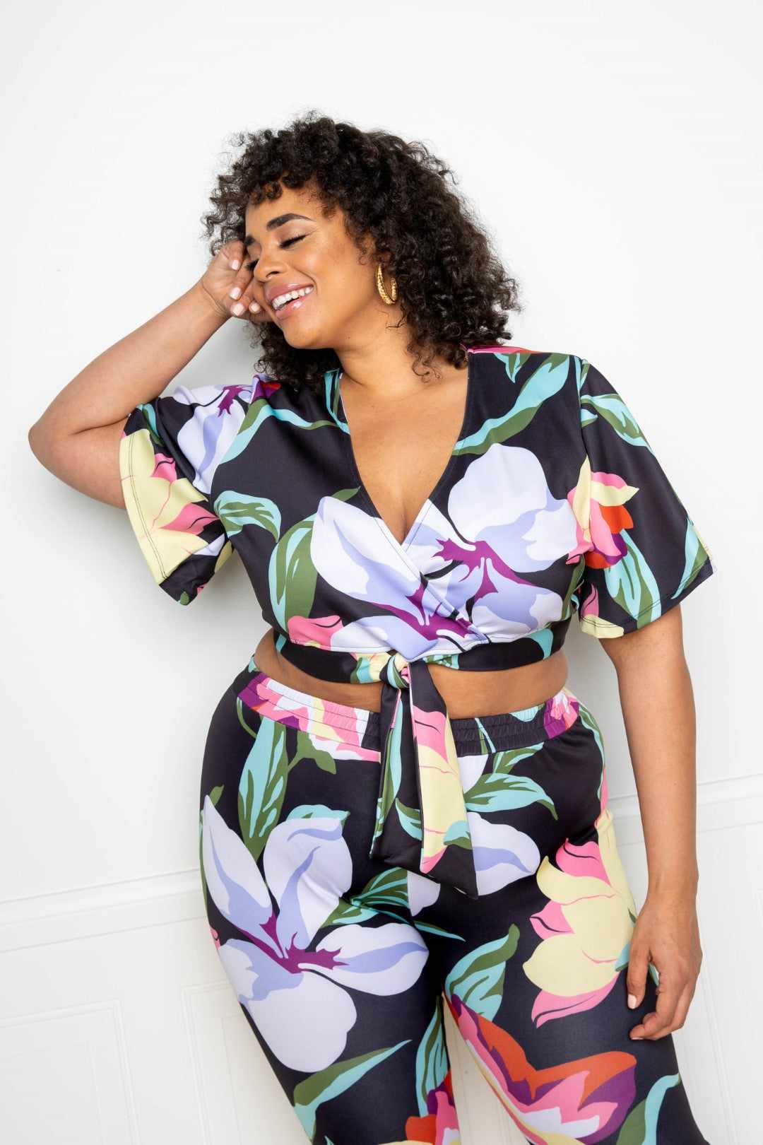 Plus-size model wearing a colorful Flower Jogger & Top Set, featuring bold floral patterns in a Multi/Black color scheme.