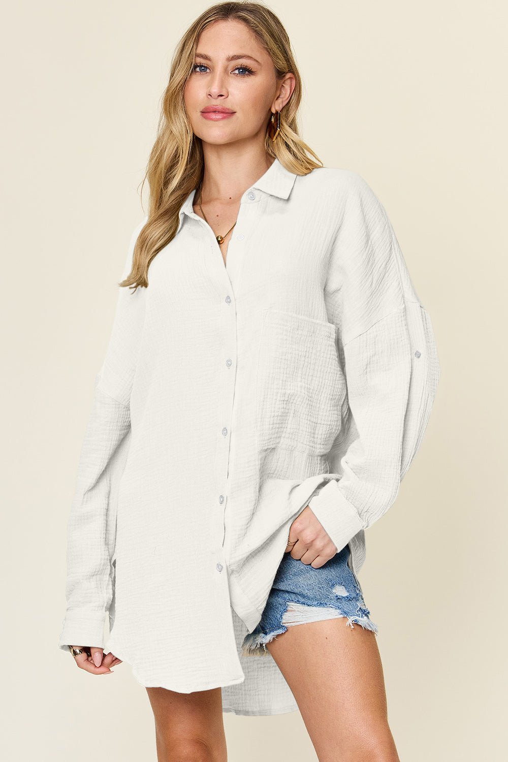 Woman wearing white full size pocketed button-up cotton shirt with slight stretch, styled with denim shorts.