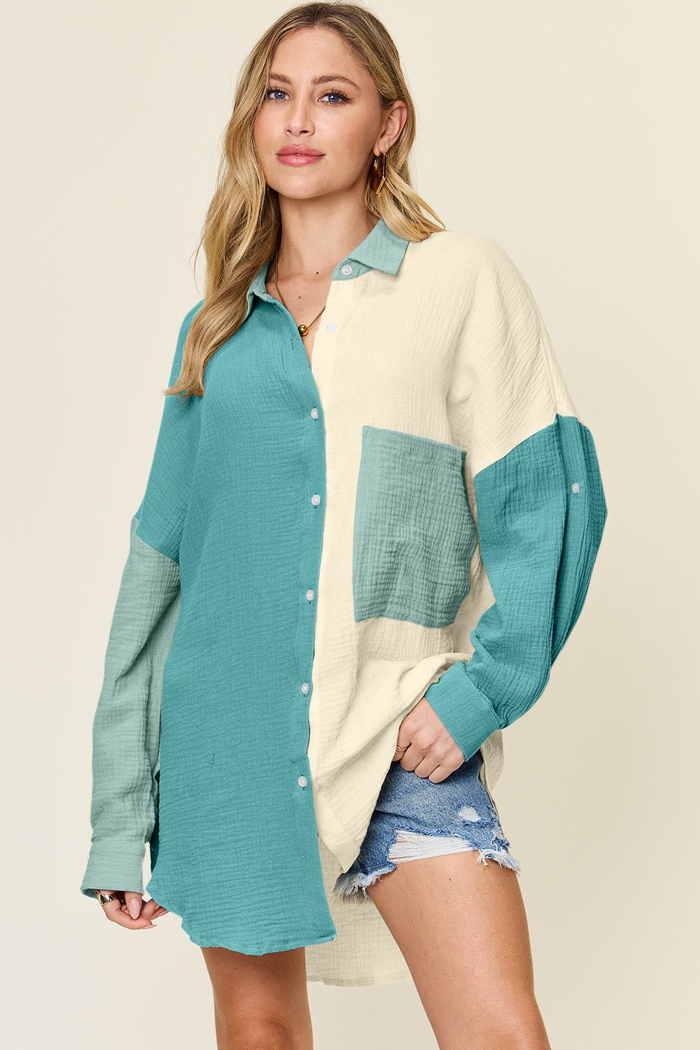 Woman wearing full-size pocketed textured button-up shirt in teal and cream, paired with denim shorts.