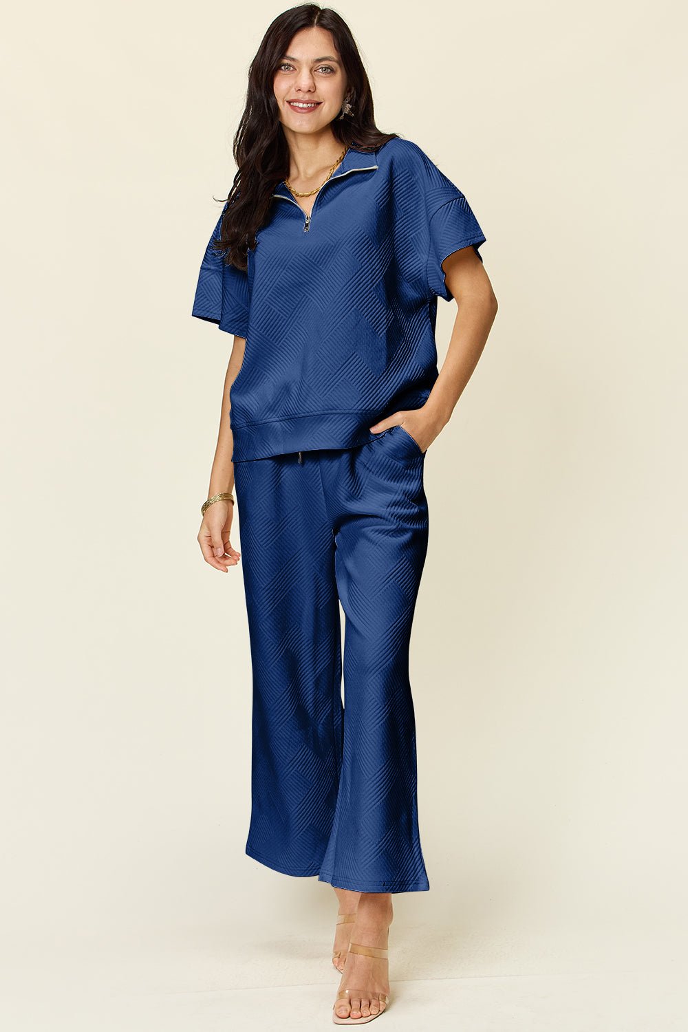 Stylish blue two-piece set with textured half zip short sleeve top and pants, featuring pockets and drawstring for a comfortable fit.