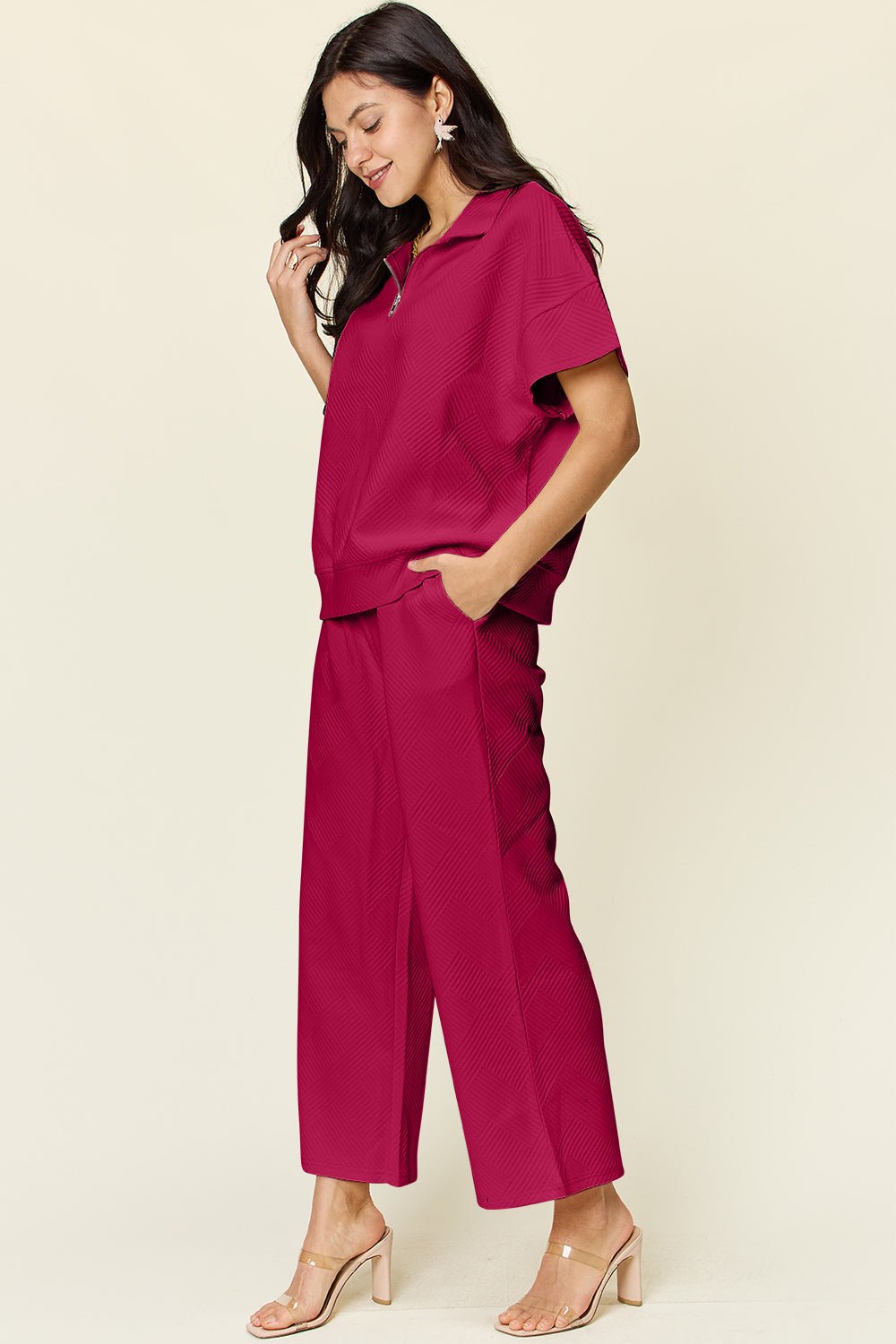 Woman wearing a full size texture half zip short sleeve top and pants set in red with pockets and drawstring, made of polyester blend.
