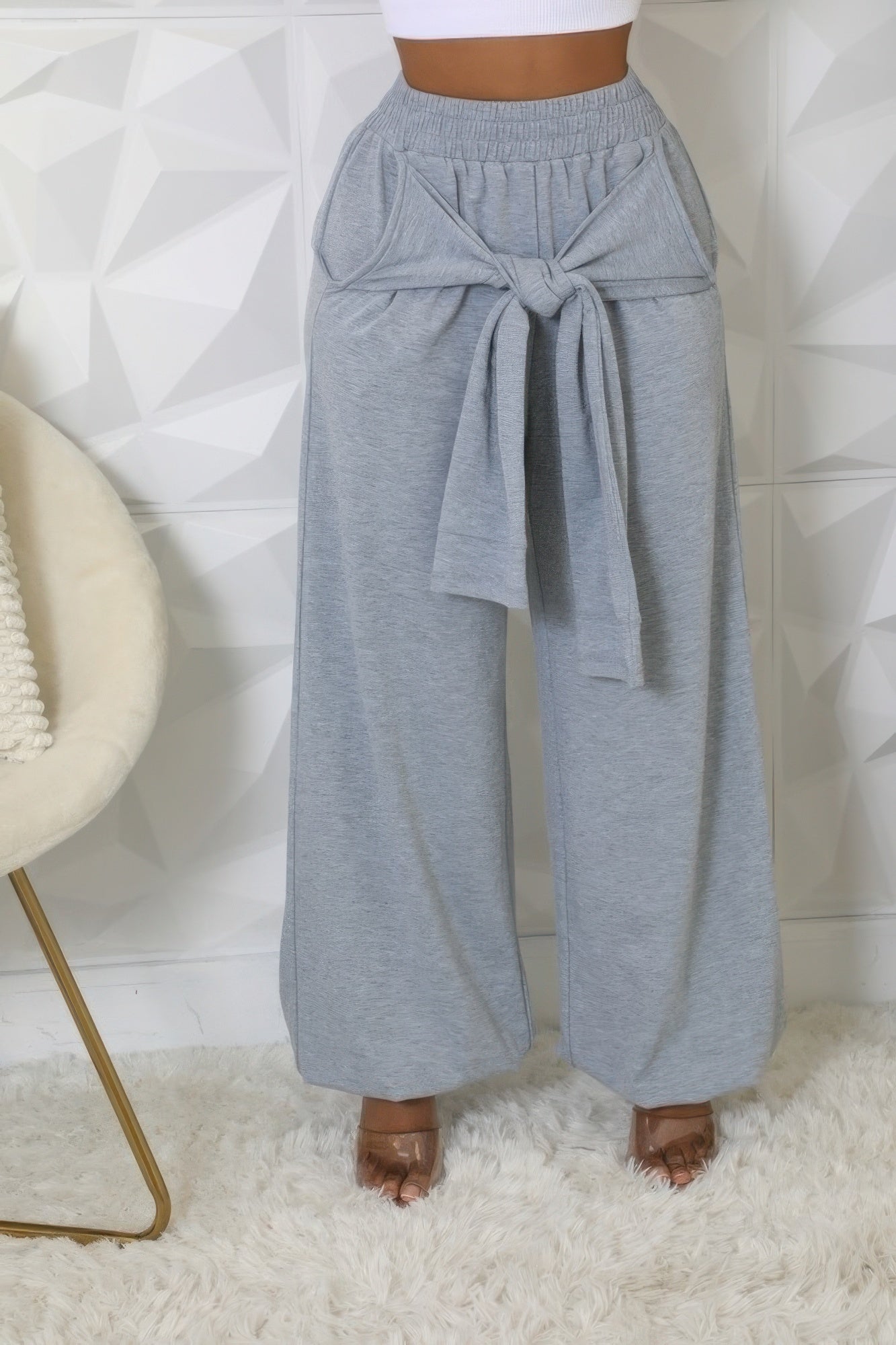 Woman wearing gray high-waisted stretch pants with elastic waistband and stylish tie detail, showcasing comfortable and trendy style.