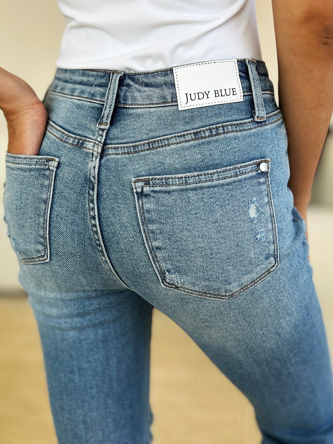 Mid rise distressed jeans with destroyed hem, featuring a back view and moderate stretch for comfort and style.
