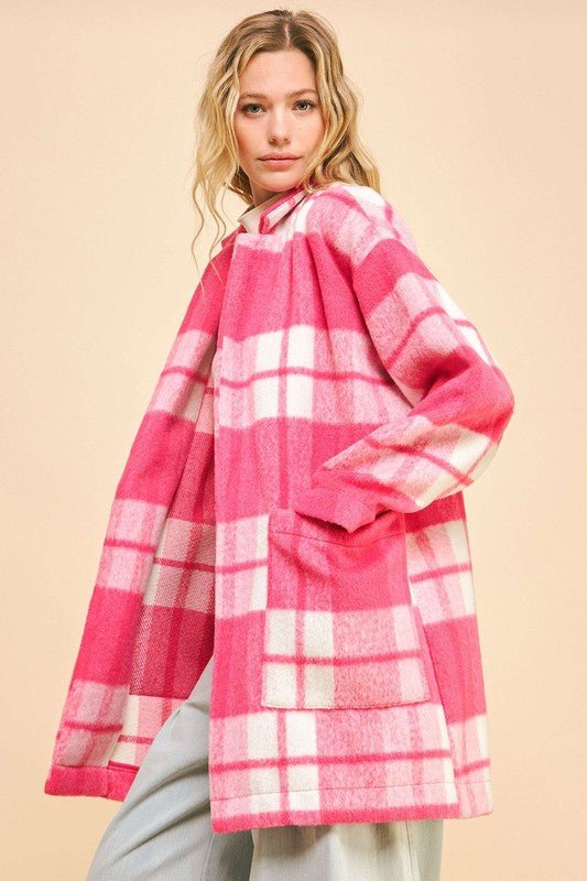 Woman wearing pink plaid open front longline coat with drop shoulders and pockets.