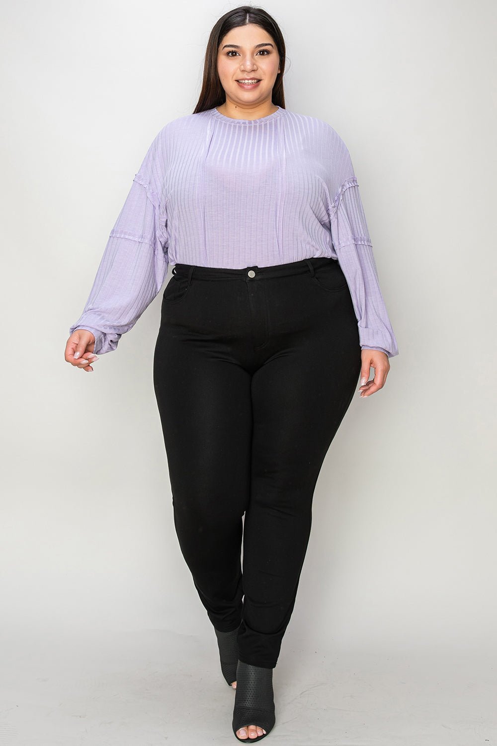 Plus-size model wearing ribbed round neck long sleeve T-shirt in lavender paired with black pants.