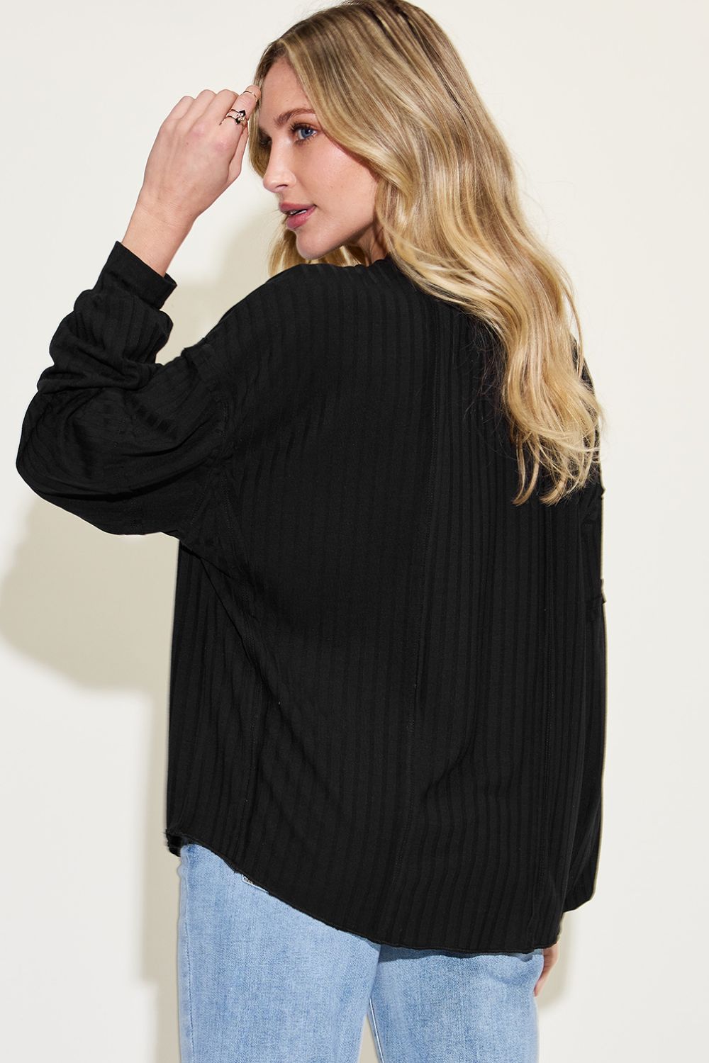 Woman wearing a black ribbed round neck long sleeve t-shirt with jeans, showcasing back view and exposed seam detail.