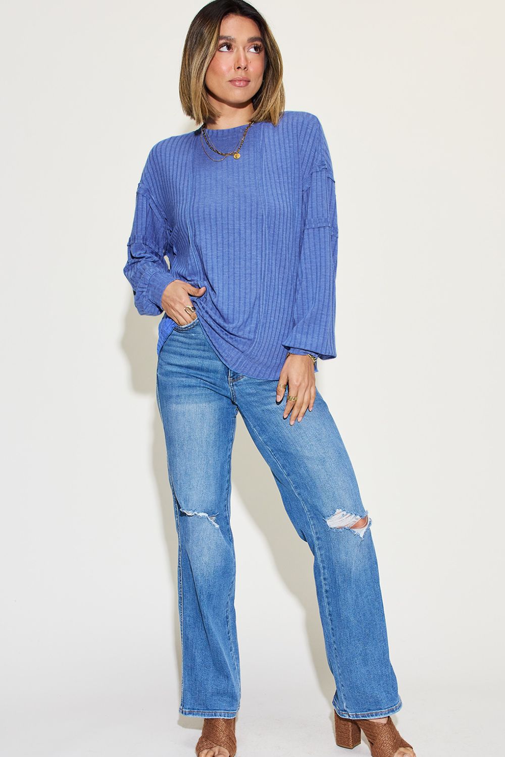 Woman wearing blue ribbed round neck long sleeve t-shirt with jeans and heels, showcasing casual fashion style.