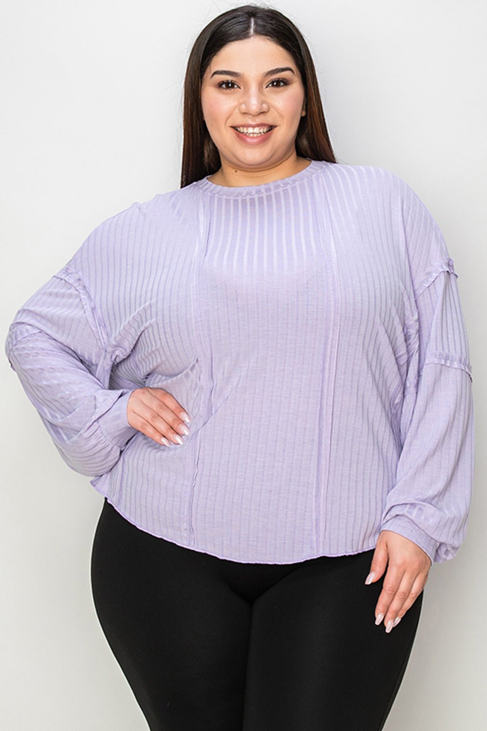 Woman wearing a ribbed round neck long sleeve purple T-shirt, showcasing moderate stretch and opaque design.