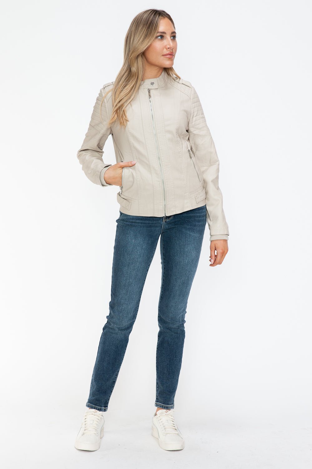 Woman wearing sand PU leather biker jacket with side zip pockets and jeans.