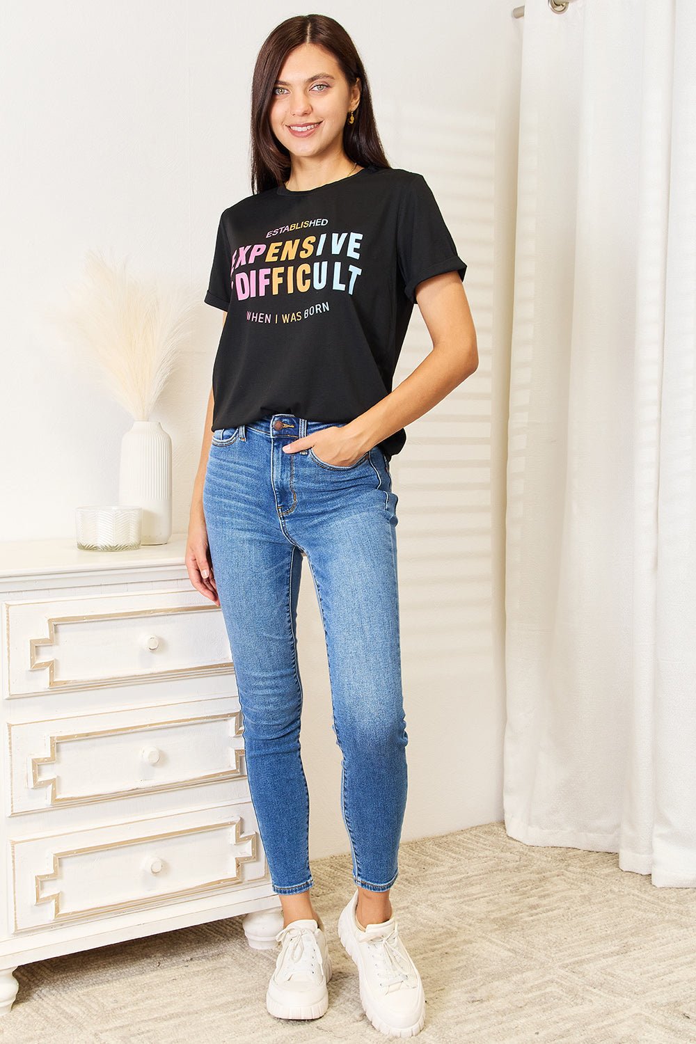 Woman wearing a slogan graphic cuffed sleeve T-shirt with jeans, showcasing versatile style and comfortable fit.